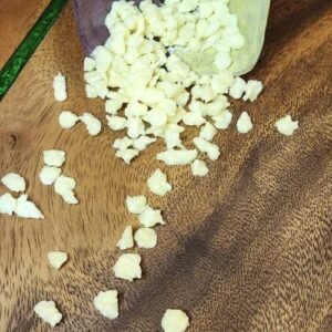 Dehydrated yogurt coconut drops spilling out of a bowl onto a dark wood board